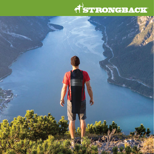 Man standing next to a lake with elite chair in bag strapped to his back.